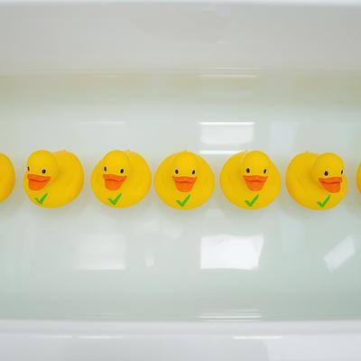 rubber ducks in a row in a bathtub, each with a green check mark